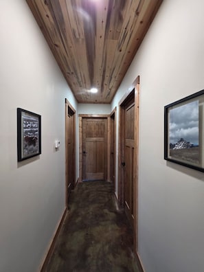 A narrow hallway with wooden walls and ceiling, a door at the end, and framed pictures on the walls. - Wonderful 3-bedroom house in Dubois perfect for your getaway peace and quiet (Dubois)