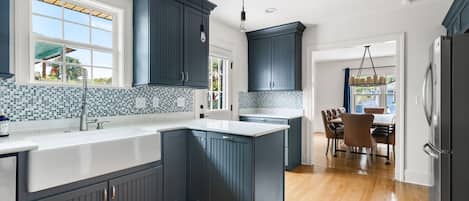 Uma cozinha com armários escuros, bancada branca e painel de azulejos.