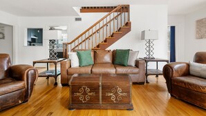 A living room with a wooden staircase, leather sofas, a coffee table, and a lamp. - Blackbeard's Isle -  9 beds, 6BR/3BA - 500 ft from Beach (Isle of Palms)
