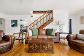 A living room with a wooden staircase, leather sofas, a coffee table, and a lamp. - Blackbeard's Isle -  9 beds, 6BR/3BA - 500 ft from Beach (Isle of Palms)