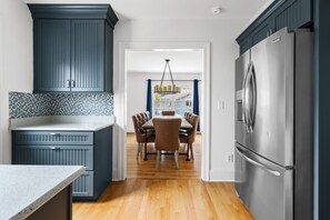 A kitchen with dark blue cabinets, a stainless steel refrigerator, and a dining area with a table and chairs. - Blackbeard's Isle -  9 beds, 6BR/3BA - 500 ft from Beach (Isle of Palms)
