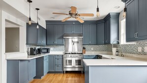 A kitchen with blue cabinets, a stainless steel stove, and a ceiling fan. - Blackbeard's Isle -  9 beds, 6BR/3BA - 500 ft from Beach (Isle of Palms)