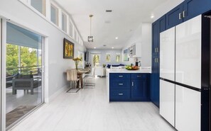 A modern kitchen with a central island, white cabinetry, and a blue accent wall.
