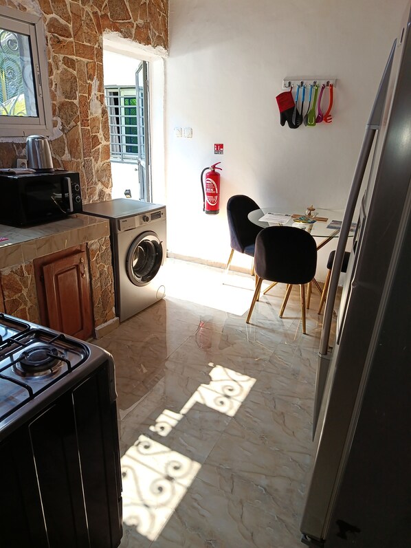 Una cocina con estufa, microondas, lavadora y extintor de incendios en la pared.