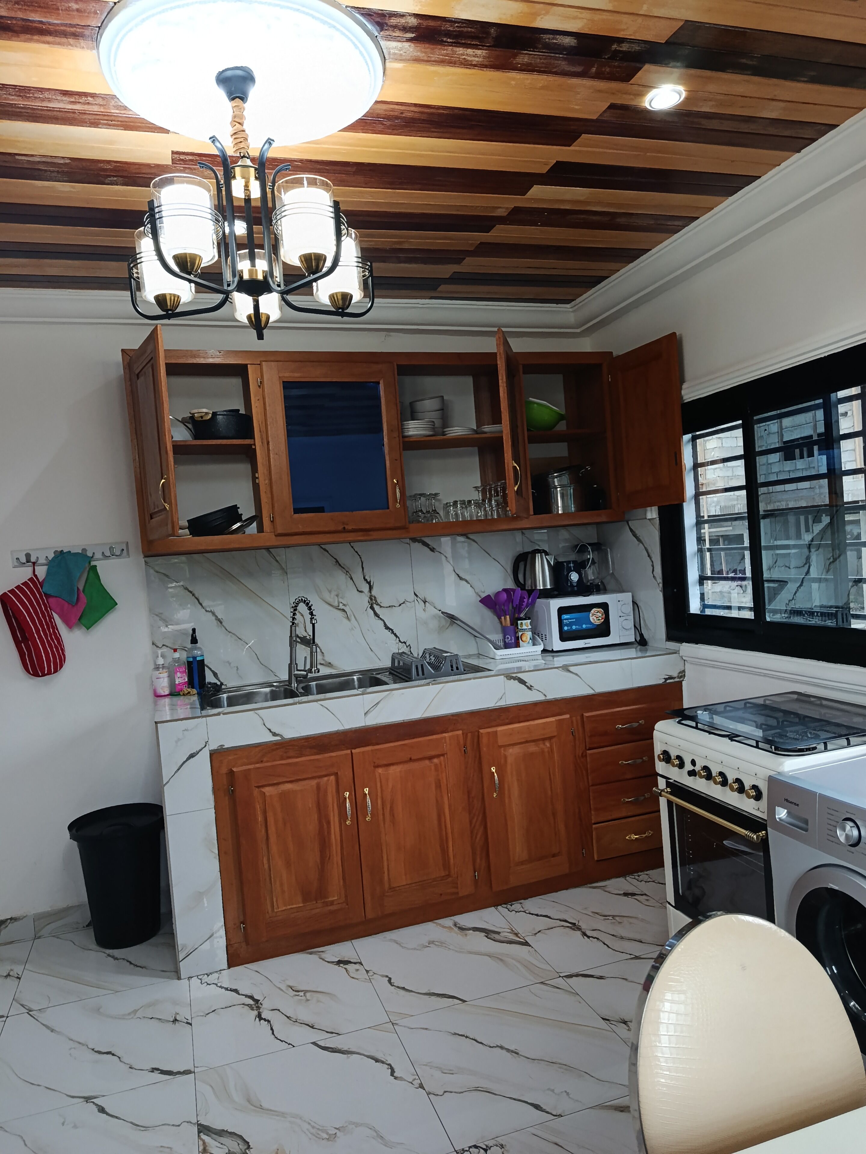 Cozinha com armários de madeira, bancada de mármore, fogão e micro-ondas.