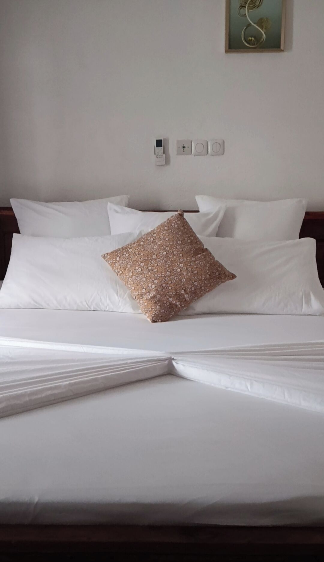 A bed with white linens and a single decorative pillow.