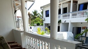 A balcony with white balustrades, a wooden bench, and a tiled floor.
