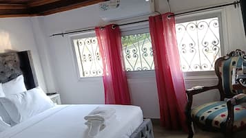 Une chambre à coucher comprenant un lit, une chaise, une fenêtre avec des rideaux et un appareil de climatisation.