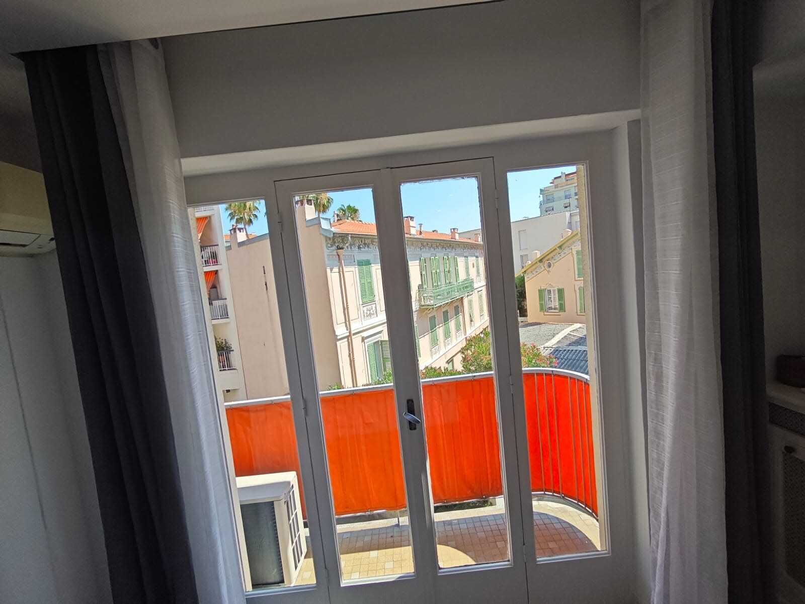 Una finestra con vista su edifici e una recinzione rossa.