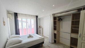 Ein Schlafzimmer mit Bett, Nachttisch, Kleiderschrank und einem Fenster mit Vorhängen.
