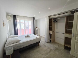 A bedroom with a bed, a bedside table, a wardrobe, and a window with curtains. - Appart 2 chambres – calme & lumineux – proche tram (Nice)