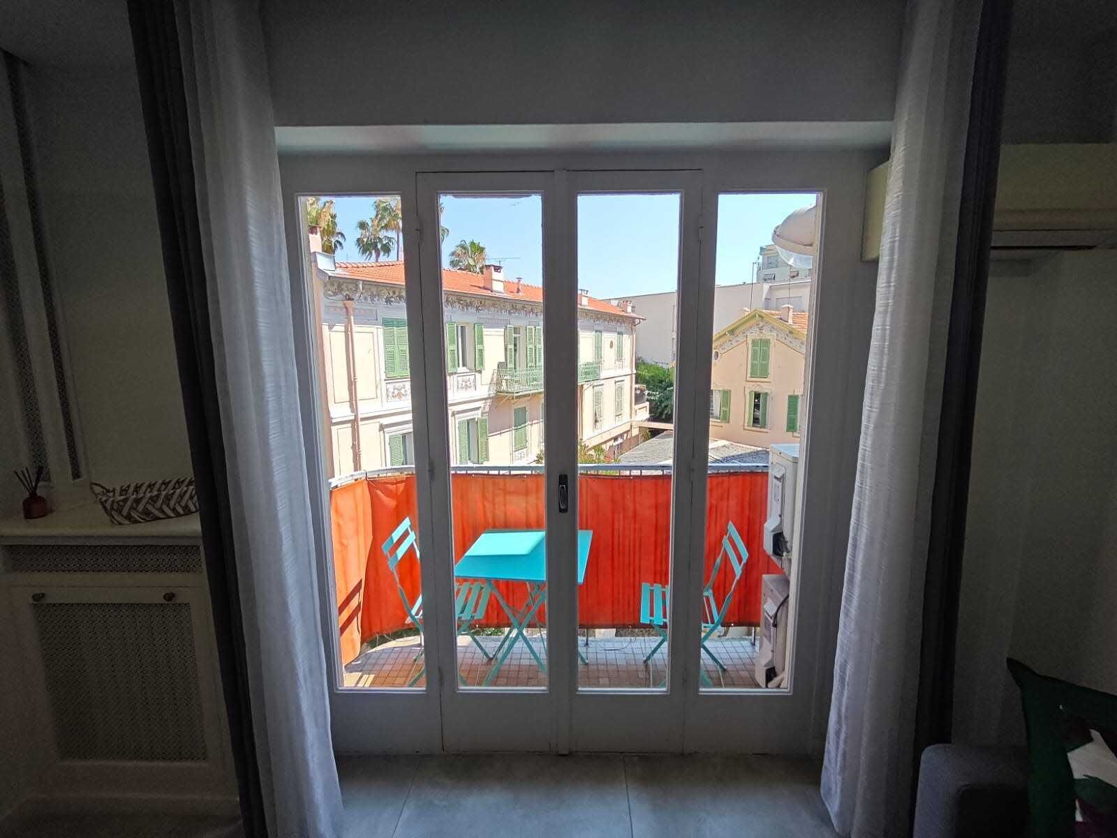 A room with a sliding glass door leading to an outdoor area with a red fence and a blue table.