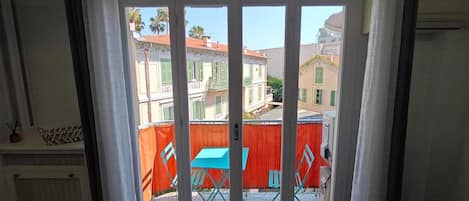Une pièce dotée d’une porte-fenêtre coulissante qui donne sur un espace extérieur avec une clôture rouge et une table bleue.
