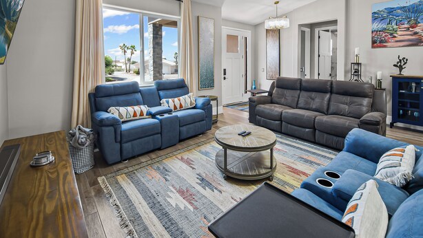 A spacious living room with two sofas, a coffee table, and a large window. - New on VRBO! New Construction, Stylish Mega RV Garage House (Lake Havasu City)