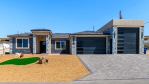 A modern two-story house with a garage, a driveway, and a landscaped front yard. - New on VRBO! New Construction, Stylish Mega RV Garage House (Lake Havasu City)