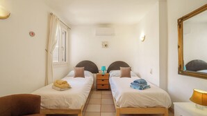 Ett hotellrum med två separata sängar, ett litet bord, en stol, en spegel och en lampa.