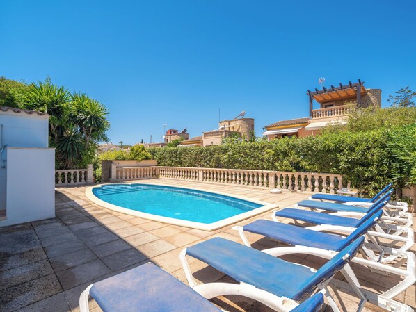 Une piscine avec des chaises longues et un mur en pierre.