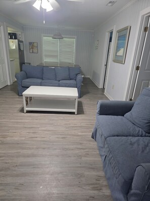 Ein Wohnzimmer mit einer Couch, einem Couchtisch und einer Tür.