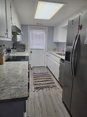 A kitchen with white cabinets, a stainless steel refrigerator, a microwave, and a gas stove. - Enjoyable 3-bedroom house with AC in Murrells Inlet (Murrells Inlet)