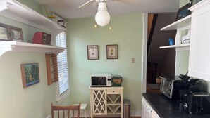 A compact kitchen with a dining table, a microwave, a coffee maker, and a dishwasher. - Pentz Howe House Apartment, (Charlottetown)