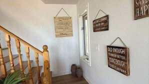 Una escalera de madera con barandilla, que conduce a un rellano con una planta en maceta.