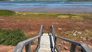 Una escalera de madera que baja a una playa, bajo un cielo despejado.
