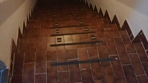 Uma escadaria estreita com soalho em azulejos que conduz a um andar superior.