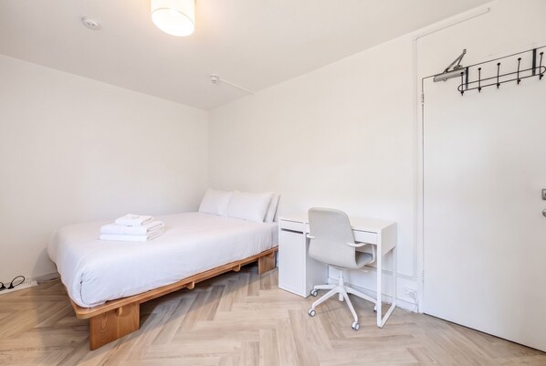 A minimalist bedroom with a bed, a desk, and a chair. - Bondi Studio, Rooftop Terrace | 2 Min Walk to Beach, King Bed, AC (Bondi Beach)