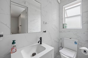 Ein Badezimmer mit einem weißen Waschbecken, Spiegel und WC.