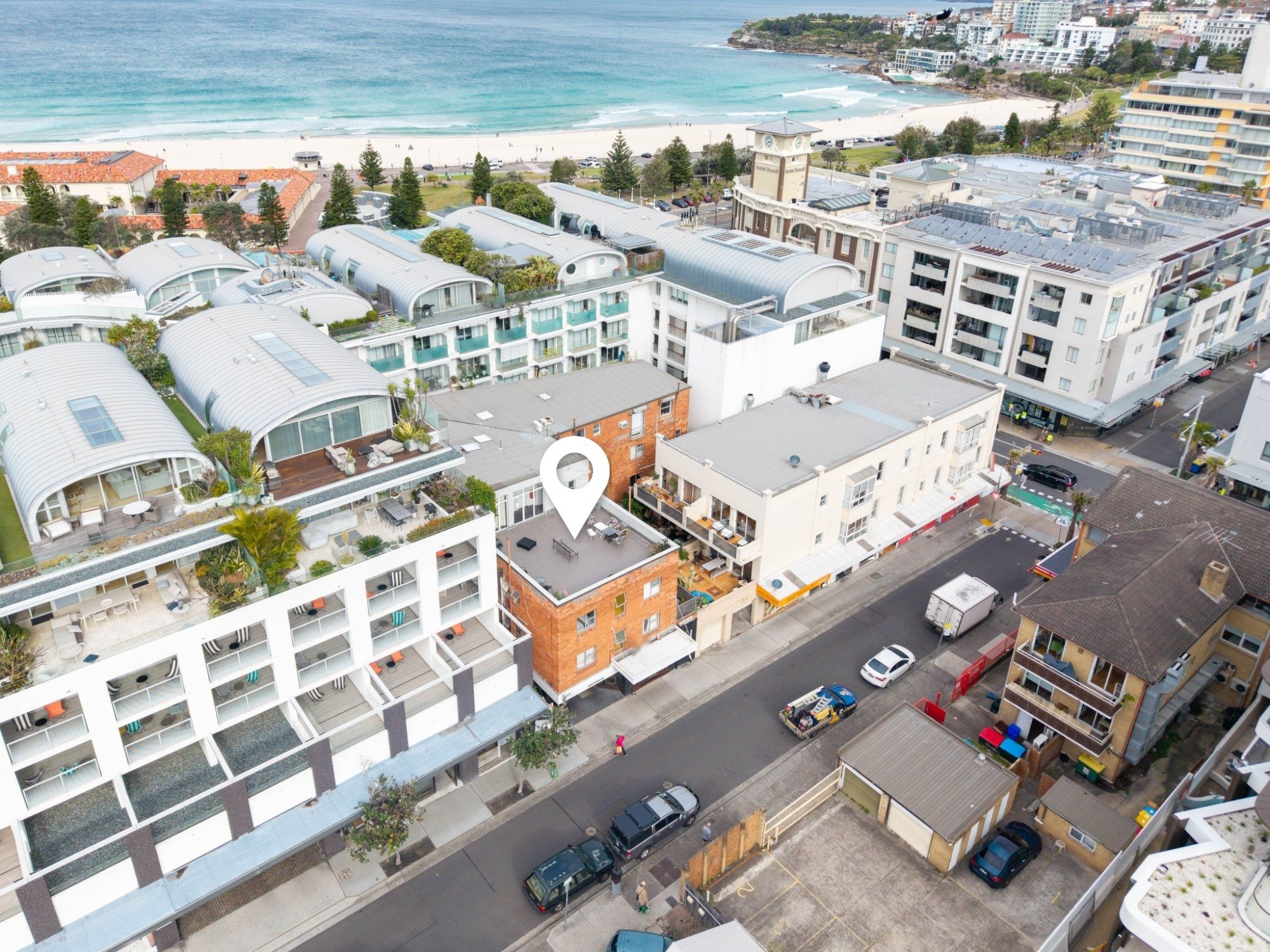 A coastal hotel with multiple floors, a rooftop terrace, and a view of the beach.