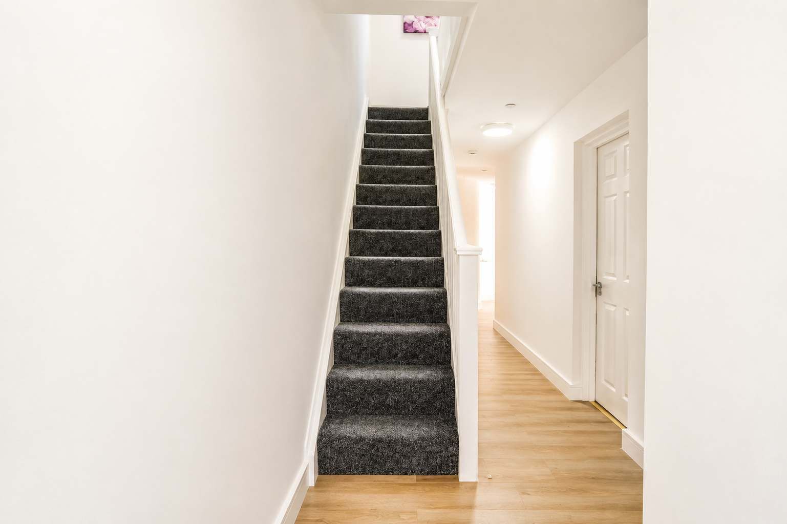 Een smalle gang met een betegelde trap die naar een deur leidt.