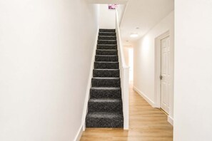 Un pasillo estrecho con una escalera alfombrada que lleva a una puerta.