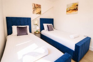Una habitación de hotel con dos camas, una mesita de noche con lámpara y obras de arte en las paredes.