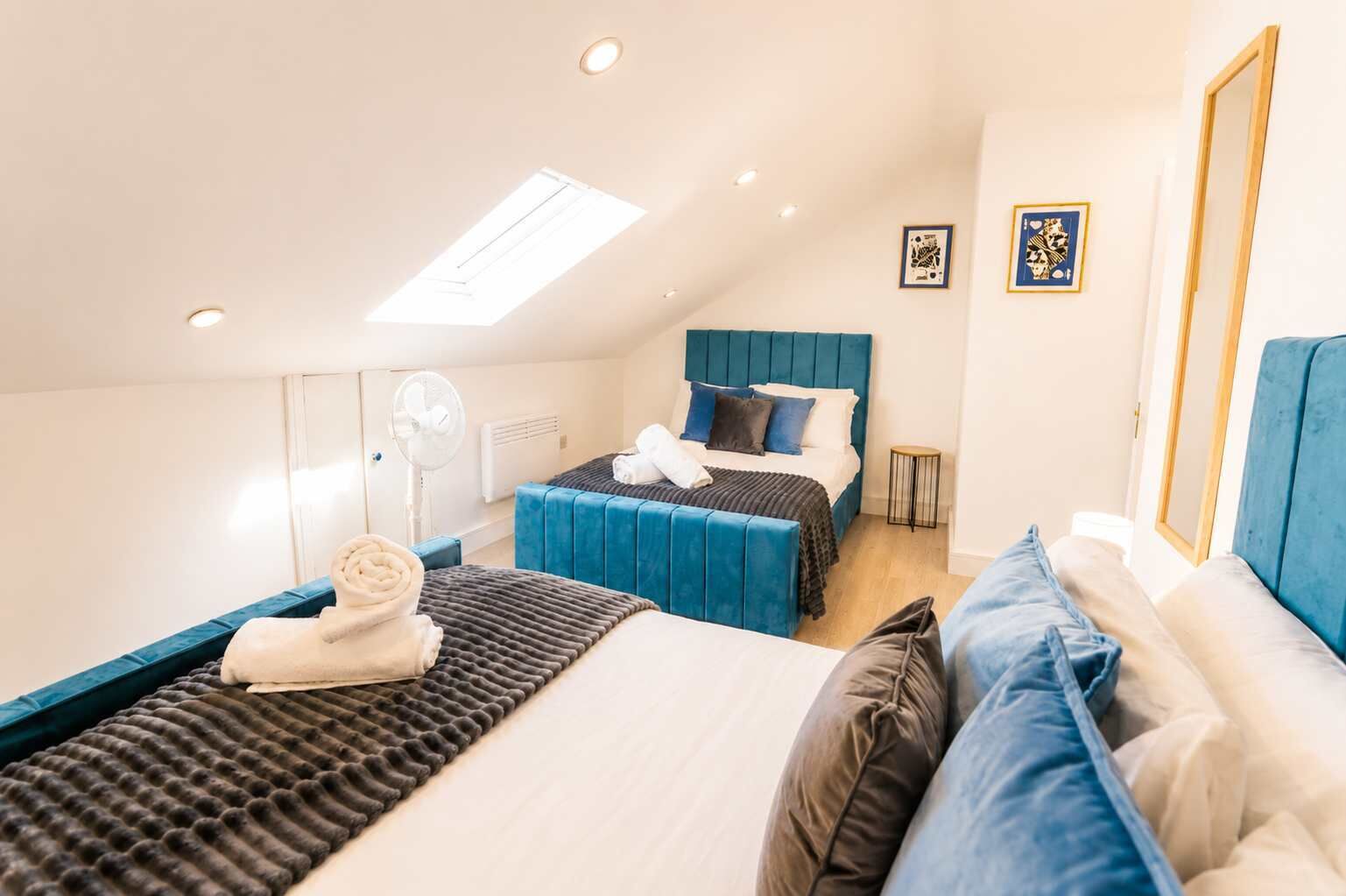 Un dormitorio con cama, una zona de estar con sofá, una mesita y un ventilador.