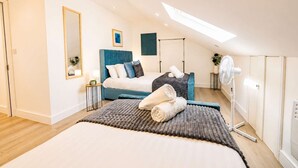 A bedroom with a large bed, a ceiling fan, and a skylight. - Spacious 3BR Flat Sleeps 10 for Groups & Family (Cardiff)