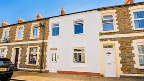A row of terraced houses with white and stone facades, a paved sidewalk, and a parked car. - Spacious 3BR Flat Sleeps 10 for Groups & Family (Cardiff)