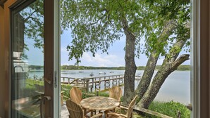 En træterrasse med et bord og stole med udsigt over en sø med både.