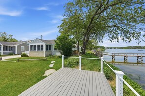 A waterfront property with a wooden deck, a covered porch, and a view of the lake. - Waterfront Cape Cottage w/ Private Beach Access (Dennis)