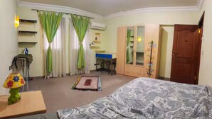 A bedroom with a bed, a desk, a wardrobe, and a chair. - Spacious 3-bedroom apartment in charming Cairo with AC (Cairo Governorate)