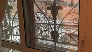 A window with decorative ironwork and a view of a balcony with a tiled floor. - Spacious 3-bedroom apartment in charming Cairo with AC (Cairo Governorate)