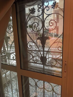 A window with decorative ironwork and a view of a balcony with a tiled floor. - Spacious 3-bedroom apartment in charming Cairo with AC (Cairo Governorate)