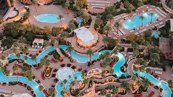 A resort with multiple swimming pools, palm trees, and lounge areas.