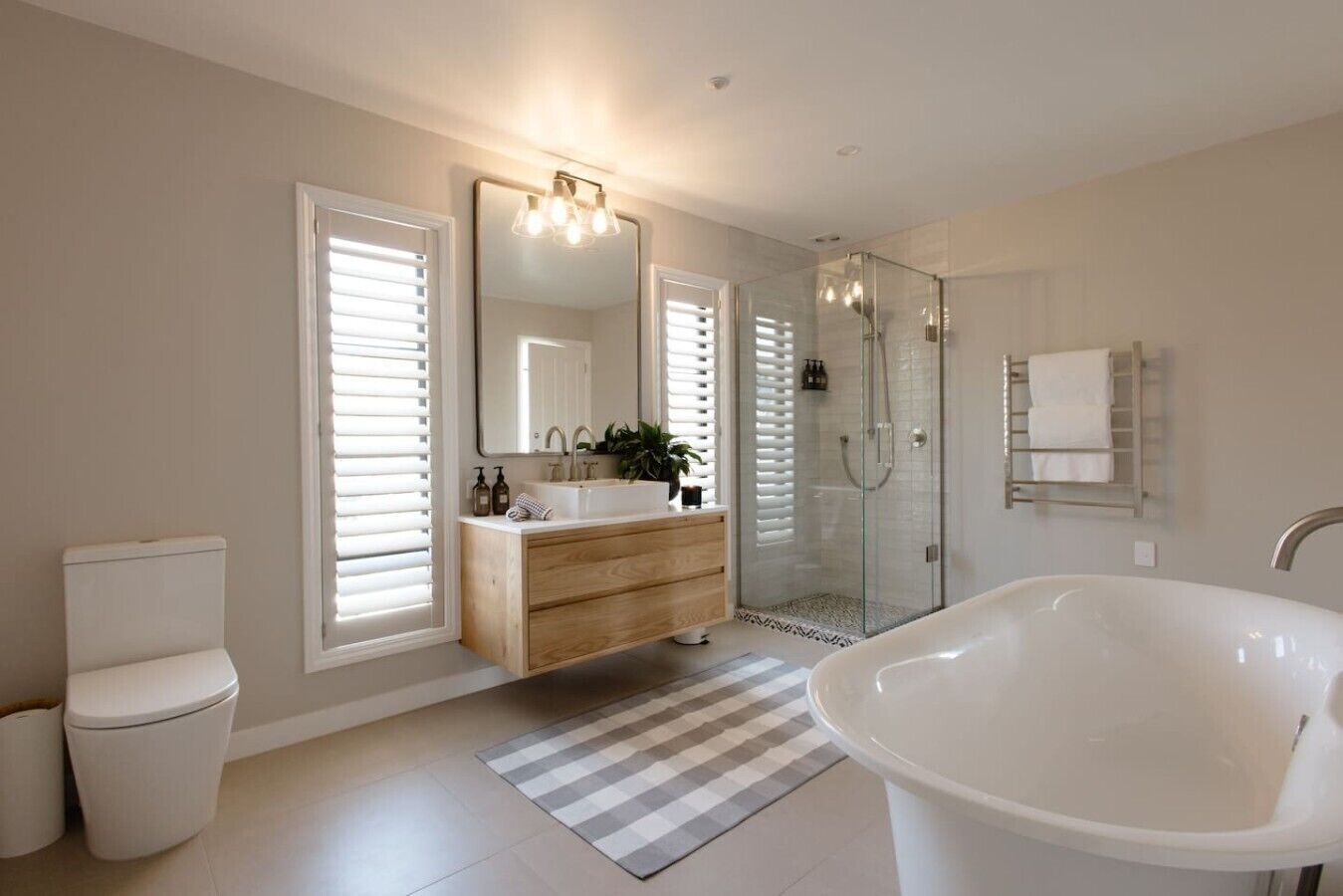 A modern bathroom with a freestanding bathtub, a glass-enclosed shower, a vanity with a mirror, and a toilet.