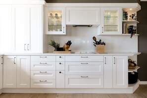 Una cocina con armarios blancos, una encimera y una estantería empotrada.