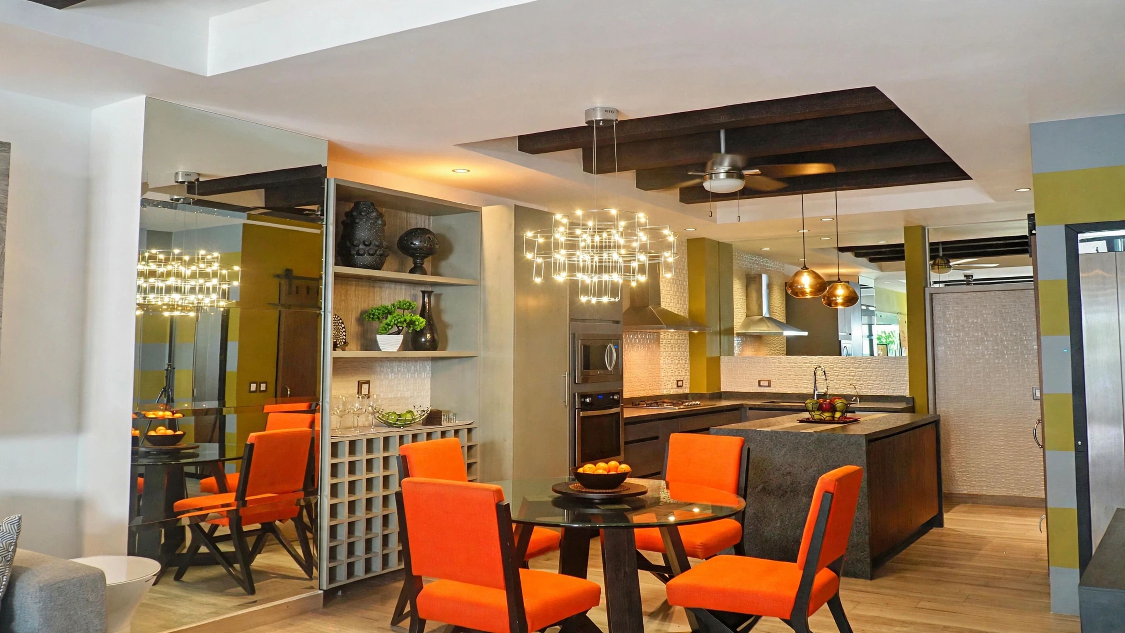 A modern kitchen with a central island, orange chairs, and a dining table.