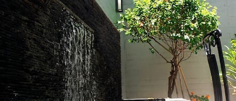 Um elemento aquático com uma parede de pedra, uma árvore e um banco.