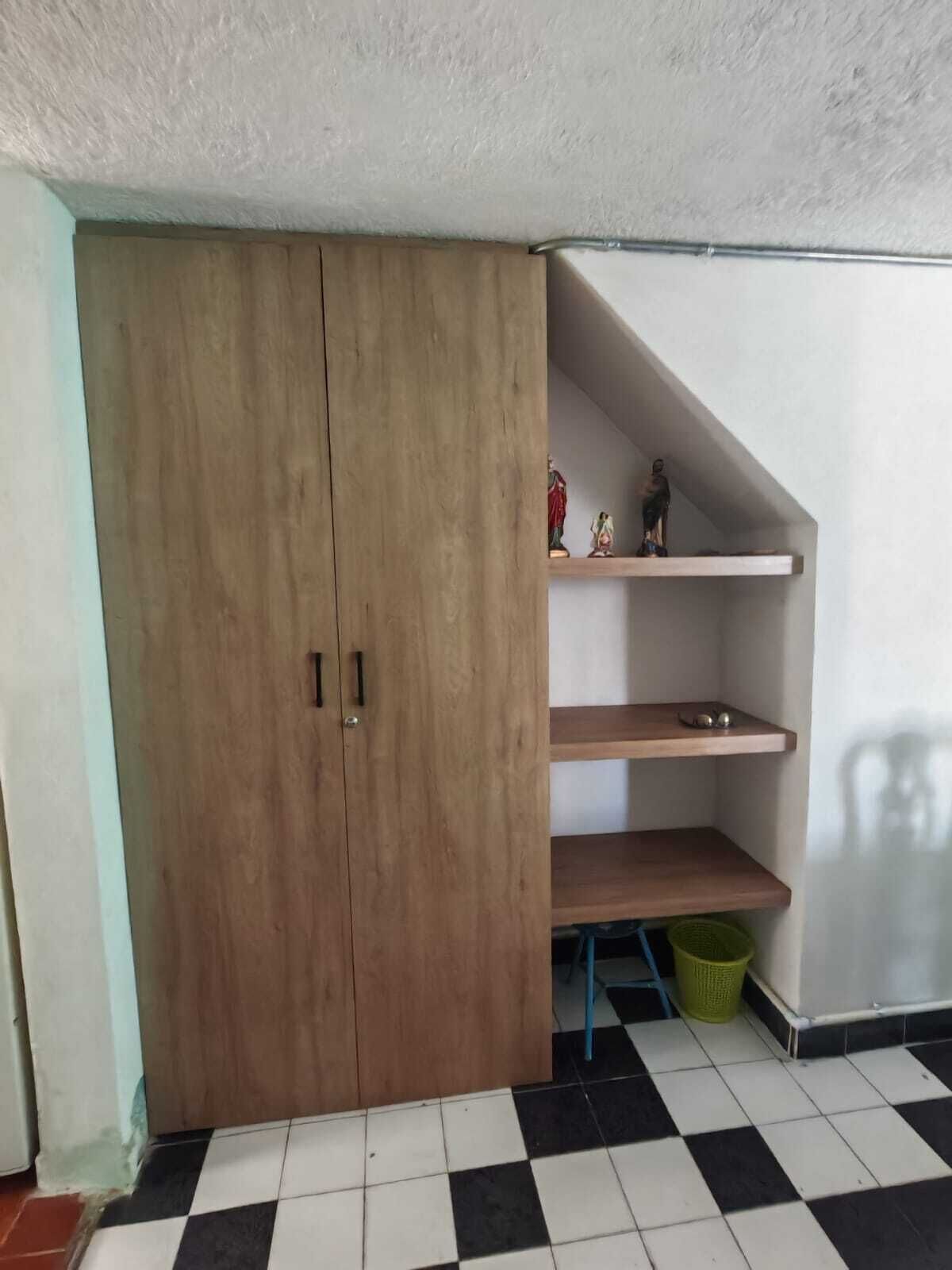 A room with a wooden wardrobe, a white wall, and a checkered floor.