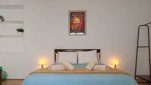 A bed with a blue quilt, two pillows, and two rolled towels on a wooden headboard. - La Alboreá (Jerez de la Frontera)