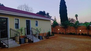 Uma casa com telhado de telhas vermelhas, parede de tijolos e entrada pavimentada.
