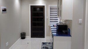 Cozinha moderna com porta escura, paredes brancas e bancada azul.